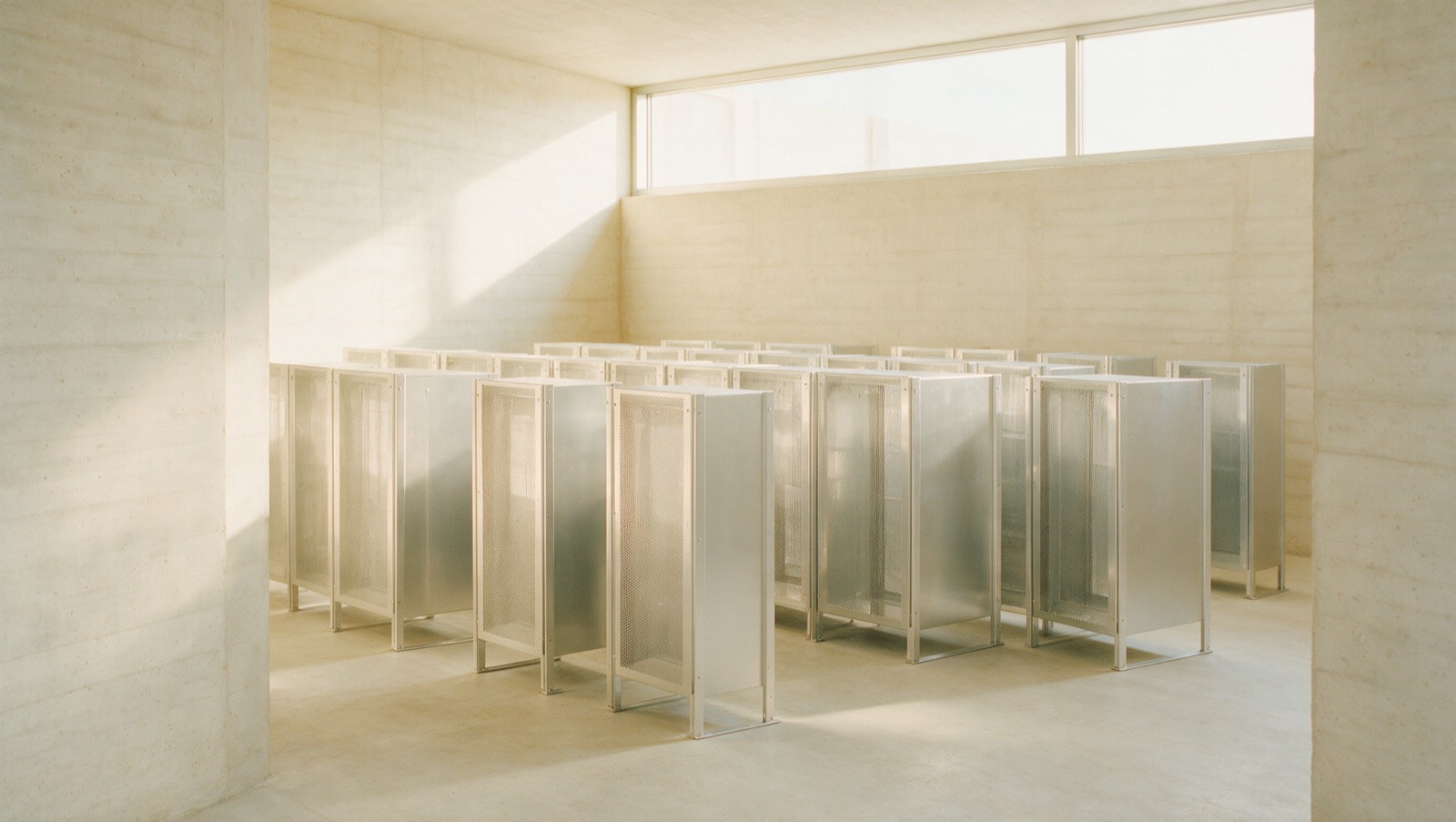 A daylit data facility interior in pale concrete and aluminium